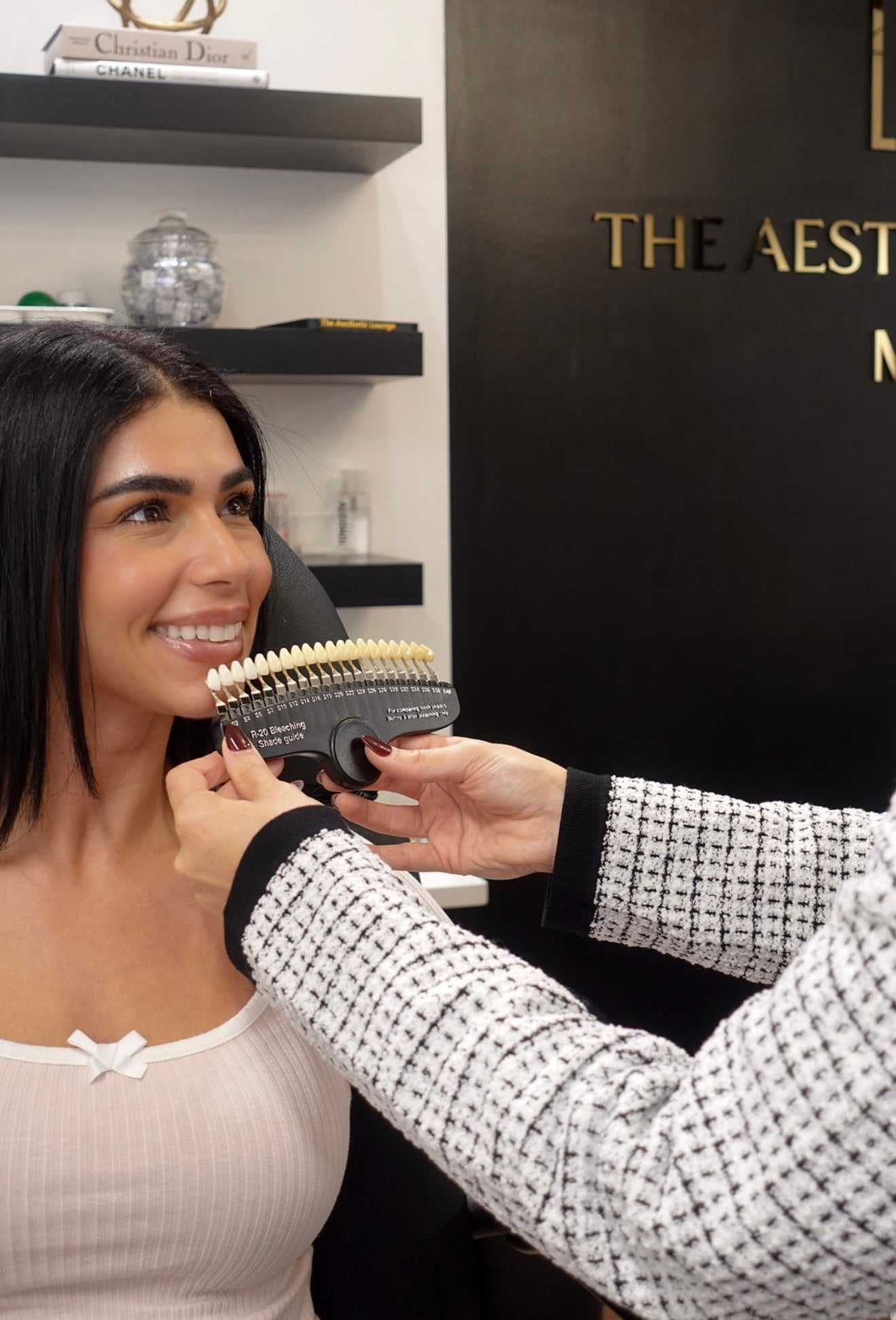 A woman smiles during a dental shade matching procedure at a clinic.