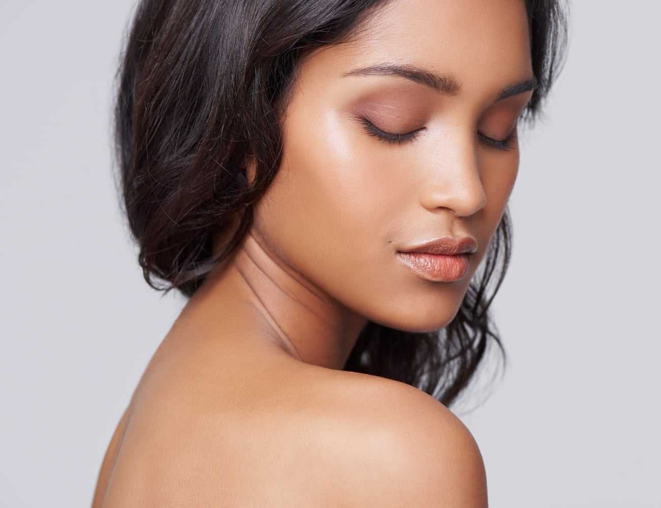 Female with smooth, glowing skin looking downward, showing radiant complexion.