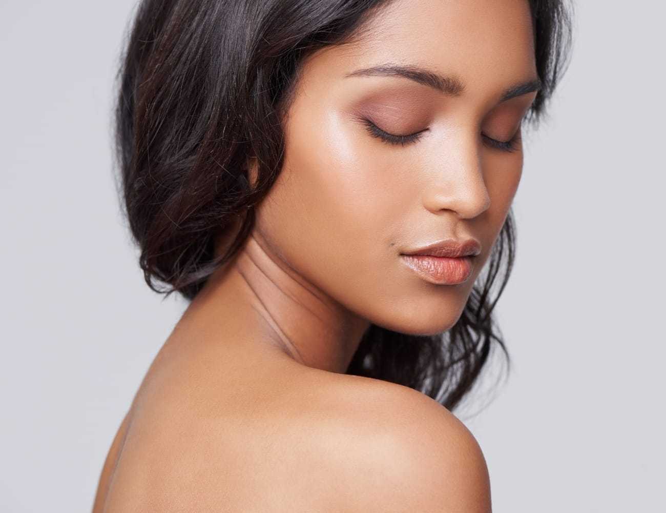 Female with smooth, glowing skin looking downward, showing radiant complexion.